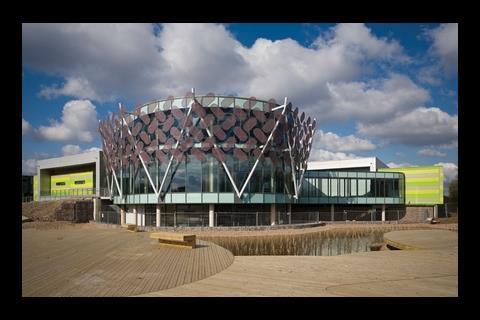 The gleaming centrepiece of Hawkins\Brown’s training centre is a glazed drum containing a car showroom cum teaching space.